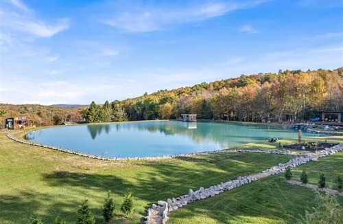 Brackney Cabin | Waterfront Tiny House Perched on the Pond Covered Deck at Water’s Edge